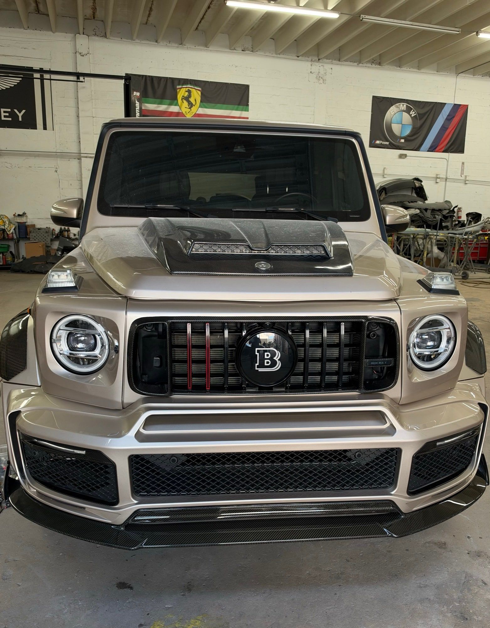 A Brabus G-wagon inside the shop, with Ferrari and BMW banners on the wall