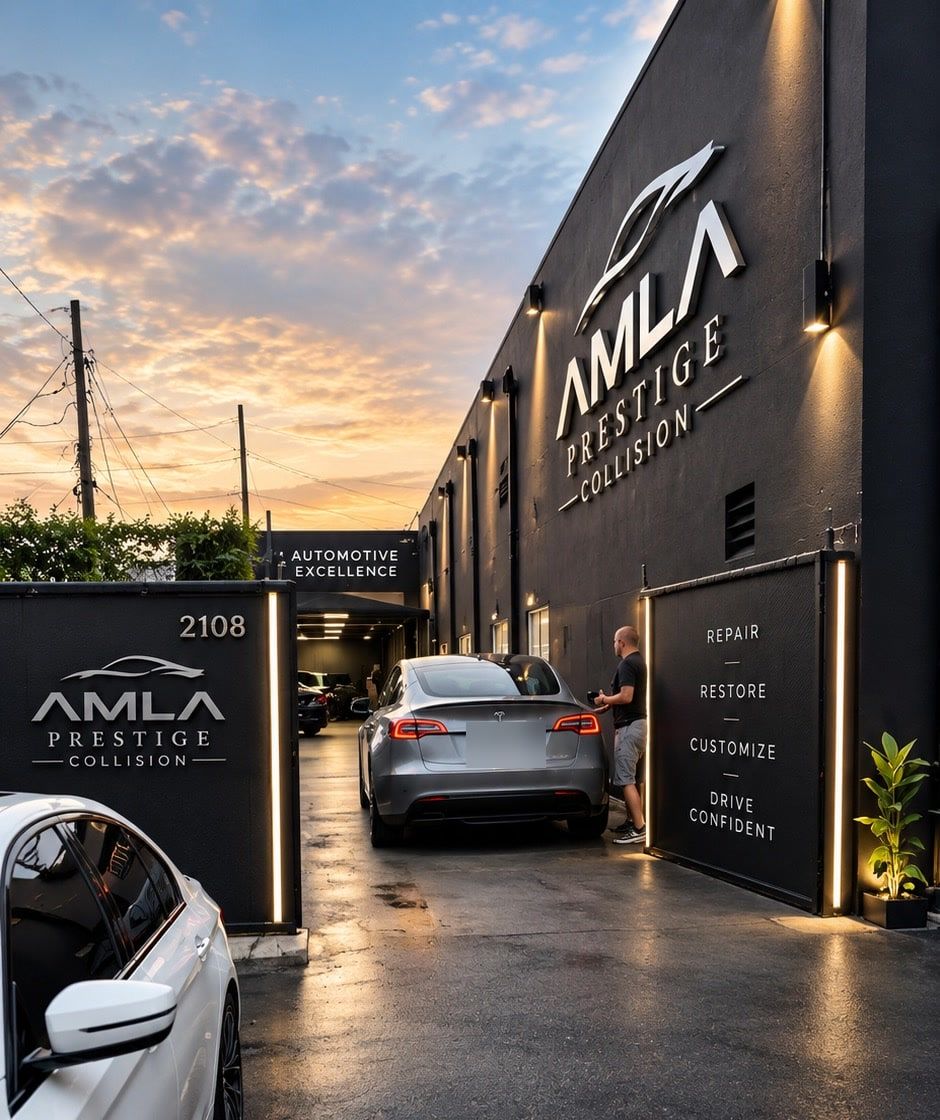 The AMLA Prestige Collision building at dusk, with its lit sign and a car in the driveway